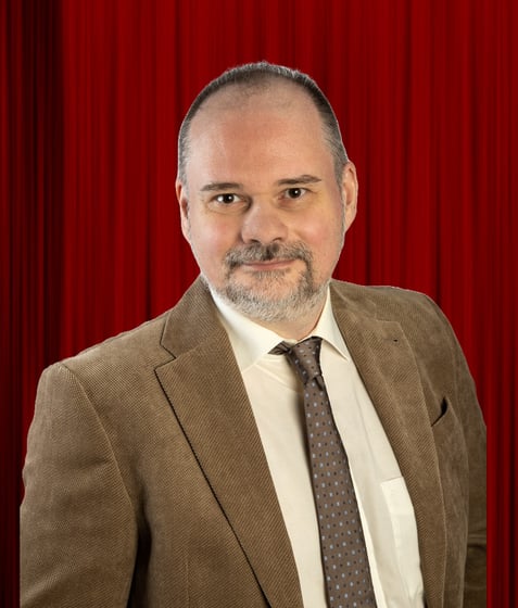 Torsten Eil im braunen Cordsakko vor einem roten Vorhang